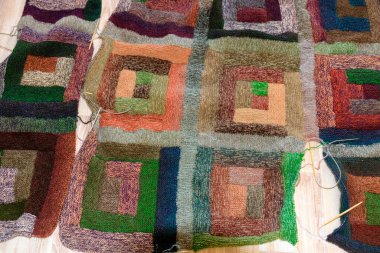 Renkli grafik tasarımı olan çeşitli örgü örülmüş bir battaniyenin yakın plan görüntüsü. Örgü örülmüş, farklı bir tarzda ekose örülmüş, farklı bir desenle örülmüş kareler.