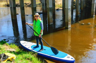 Nehirde yüzmeyi seven bir kadın, köprünün yanında nehir manzarası, güneşli bahar günü, doğada bahar zamanı, aktif dinlenme kavramı.