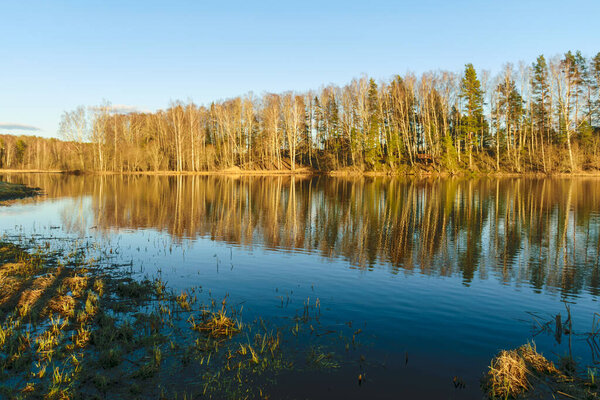 красочный весенний пейзаж с отражениями озер, облаков и деревьев на спокойной водной поверхности