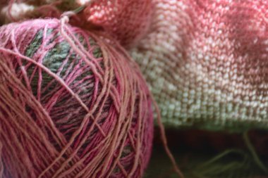 picture with variegated color balls on the knitted textile background, wool yarn and knitting tools - knitting in progress