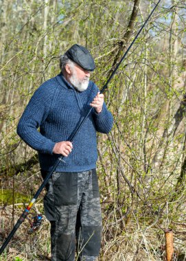 Bir balıkçıyla bahar manzarası, balıkçı oltaları denetliyor, göl kıyıları, doğada bahar.