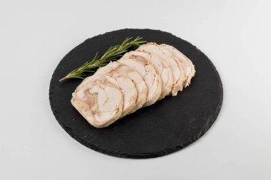 Beyaz arka planlı siyah bir tabakta biberiyeli rulo domuz eti parçaları..