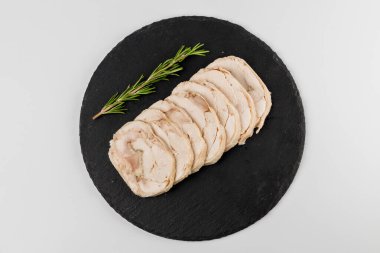 Beyaz arka planlı siyah bir tabakta biberiyeli rulo domuz eti parçaları..