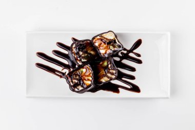 Geleneksel Japon mutfağından suşi şeklinde çikolatalı tatlı. Beyaz arkaplanda beyaz bir plaka.