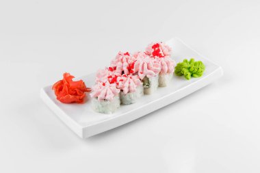Beyaz arka planda krem peynirli lav rulosu. Üzerine pembe krema ve karides konmuş suşi ruloları..