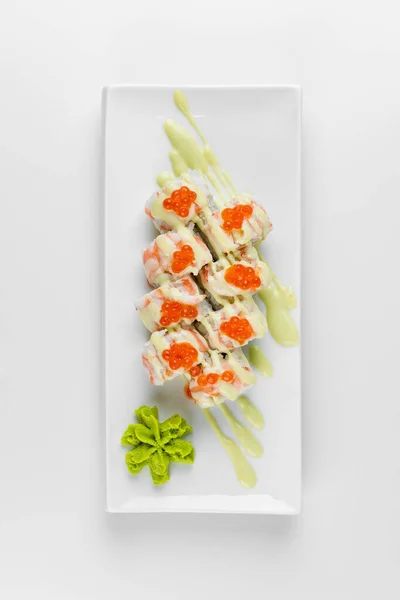 Kırmızı havyarlı suşi rulosu, beyaz bir tabakta pilav ve salatalık. Wasabi ve pembe zencefil.