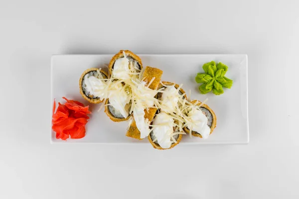 Japon tempura suşisi beyaz tabak ve arka planda. Suşi parçaları, yılan balığı, salatalık, krem peynir, avokadoya sarılmış pirinç..
