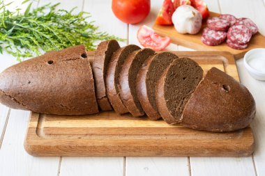 Ev yapımı çavdar ekmeği, beyaz arka planda tahta bir tahta üzerinde dilimlenmiş. Yakın plan.