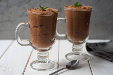 Kahvaltıda tatlı. Beyaz bir masada cam bardakta çikolatalı puding..