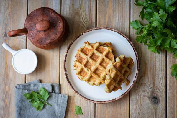 Öğle yemeği için doyurucu bir atıştırmalık: beyaz tabakta kalın patates waffle 'ı. Üst görünüm