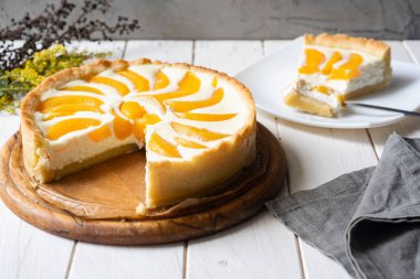 Lezzetli kahvaltı: Tahta tabakta şeftalili turta. Şeftalili turta ve beyaz bir masada süzme peynir..