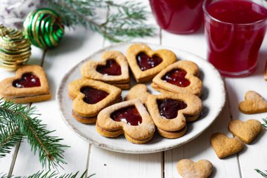 Dessert for breakfast: Delicious cookies with cherry jam in the shape of a heart on a plate on a white background.