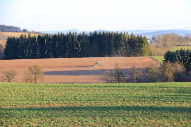 April 7 2018 - Saxony, Germany: Tractor working on the farm, a modern agricultural transport, a farmer working in the field, fertile land, tractor on sunset background, cultivation of land, agricultural machine