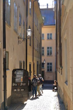 24 Mayıs 2022 - İsveç 'te Stockholm: Riddarholmen' de kaldırımda yürüyen turistler Gamla Stan 'in bir parçasıdır.
