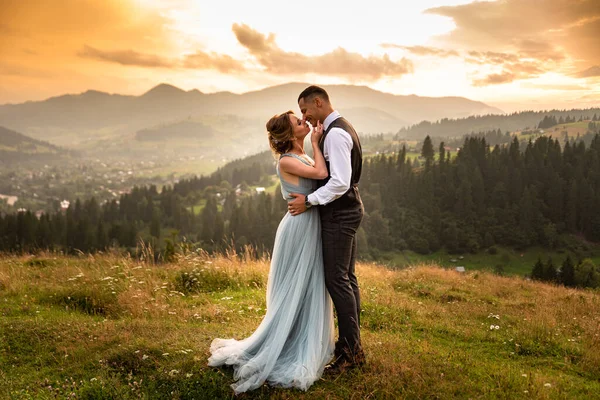 在山上举行婚礼 美丽的一对新娘在山中日落的背景下亲吻着一座山 免版税图库图片