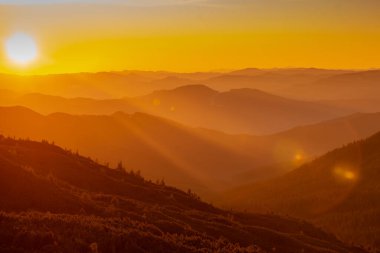 Dağların üzerinde güzel günbatımı; turuncu günbatımında orman