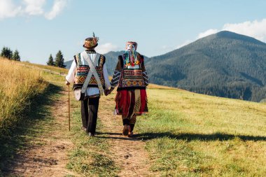 Beauty wedding couple in traditional clothes over mountains background. Ukrainian folklore wedding, culture, ethical traditions, concept.