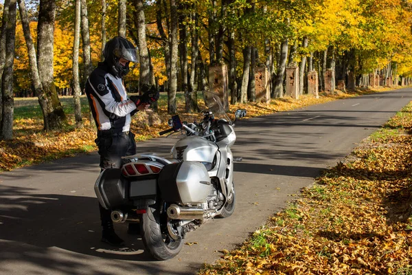 Kierowca motocykla zakłada rękawiczki motocyklowe na ręce. Mężczyzna w kasku motocyklowym, bezpiecznej jazdy. Podróżuje sam na motocyklu. Mińsk Białoruś, wrzesień 2021 — Zdjęcie stockowe