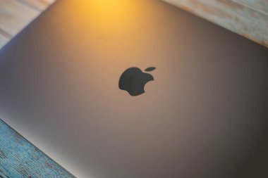 Elma logolu Macbook 'un arkası. Logo, işaret, elma sembolü. Dizüstü bilgisayarın üst kapağını kapat. Sarı ışık sol üstten düşer. Macbook profesyoneli. Tahta masada. 4 Aralık Belarus Minsk