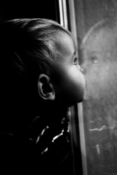 Mały chłopiec wygląda przez okno, odbicie chłopiec w oknie — Zdjęcie stockowe