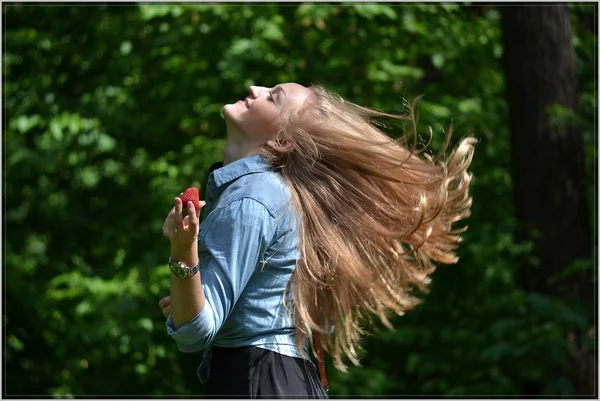 Blondes junges Mädchen in moderner Kleidung hält Beeren in den Walderdbeeren — Stockfoto