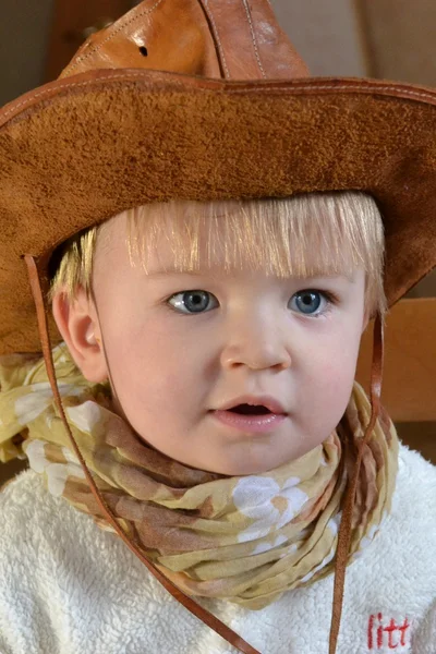 Retrato de um menino em um chapéu de cowboy e um cachecol marrom claro — Fotografia de Stock