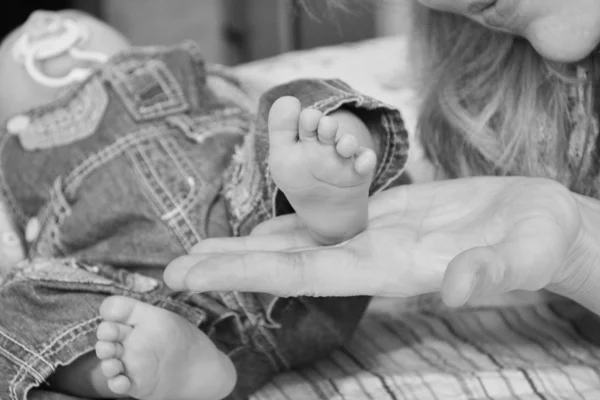 Hands and feet of a newborn baby in the hands of the mother in black and white — Stock Photo, Image