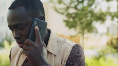 Genç Afro-Amerikan bir adamın kahve fincanı ile dışarıda dikilirken ve cep telefonuyla konuşurken göğsünü dik tut.