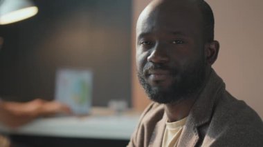 Yüzüne sakal takmış, kameraya bakan yakışıklı Afro-Amerikan bir adamın yatay, orta boy, yavaş çekim görüntüleri.
