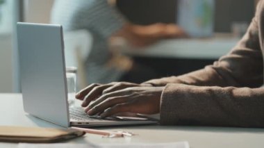 Yatay yan görüntü, tanınmayan bir iş adamının kafede oturmuş laptoptan bir şeyler mesaj atarken görüntüsü.