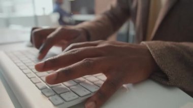 Ofisteki bilgisayar klavyesinde yazı yazan tanınmayan Afrikalı Amerikalı erkeklerin yatay yakın çekim görüntüleri.