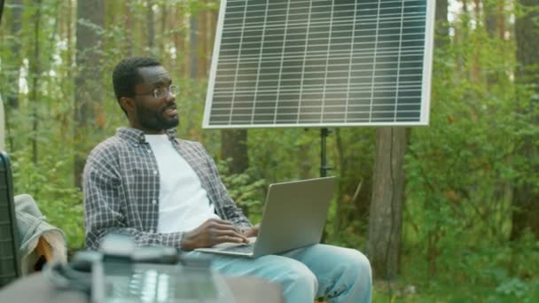 Современный Афроамериканец Сидит Стуле Лесном Серфинге Интернет Ноутбуке Используя Солнечную — стоковое видео