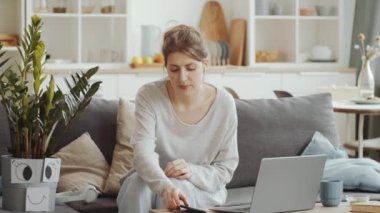 Kablosuz kulaklıklı genç bir kadın kanepede uzanıyor ve evde kilit altında tek başına kalırken hayali arkadaşıyla birlikte ev bitkisi olarak müzik dinliyor.