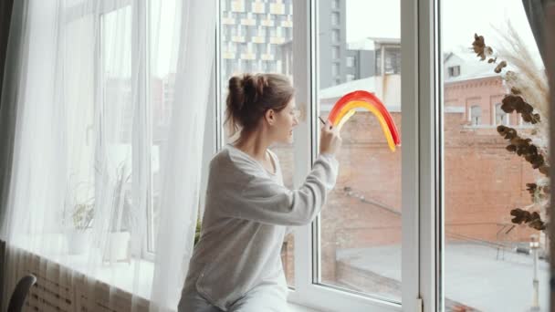 Jonge Vrouw Zittend Vensterbank Tekenen Regenboog Met Verf Borstel Vensterglas — Stockvideo