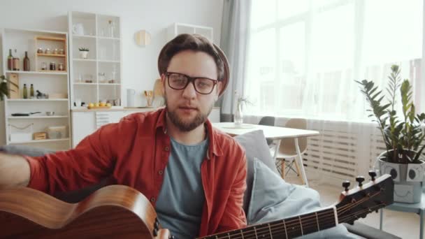 Jovem Músico Sexo Masculino Sentado Sofá Casa Tocando Guitarra Cantando — Vídeo de Stock