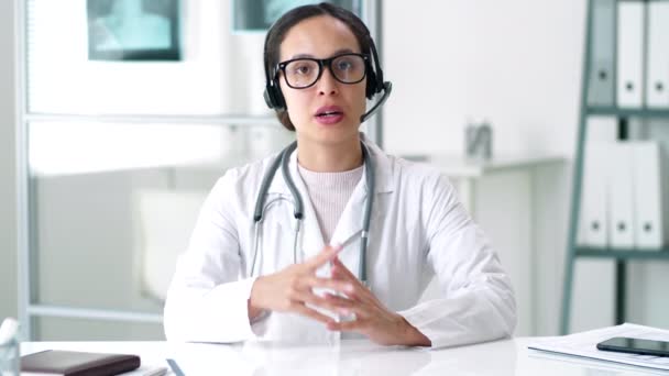 Profissional Médico Jaleco Óculos Fone Ouvido Sem Fio Sentado Mesa — Vídeo de Stock