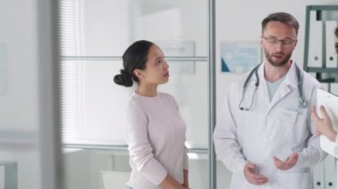 Erkek doktor ve bayan meslektaşı sağlık muayenesinden sonra sağlık ofisinde durup, bir kadınla el sıkışıyorlar.