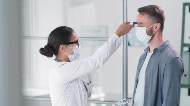 Vrouwelijke Arts Medisch Gezichtsmasker Scannen Voorhoofd Van Mannelijke Vrouwelijke Patiënten — Stockvideo