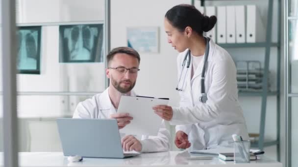 Young Brunette Female Doctor Walking Male Colleague Leaning Desk Giving — Stock Video