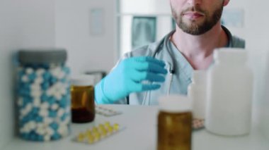 Kafkasyalı doktor üniformalı ve steril eldivenli bir adamın duvar dolabının içine bak. Raftan ilaç alıyor ve klinikteki çalışma saatlerinde uzaklaşıyor.