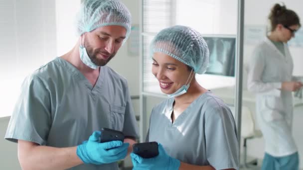 Erkek Kadın Hastane Çalışanları Tatilde Akıllı Telefonlarından Sosyal Medyayı Izlerken — Stok video