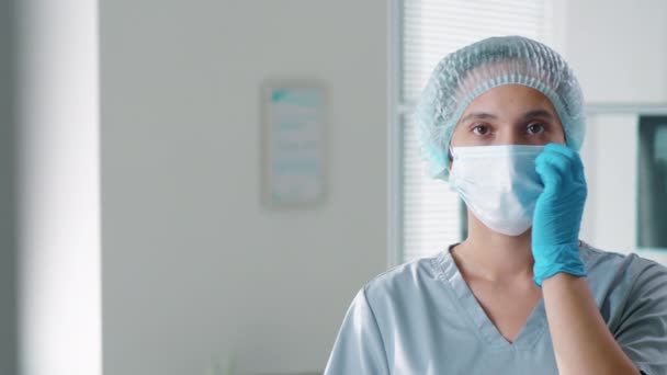 检查那些戴着一次性帽子和刷子站在医务室里的漂亮女护士的照片 摘下防护面具 自信地看着相机 Covid 19大流行病概念 — 图库视频影像