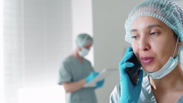 Hermosa Doctora Uniforme Protector Sombrero Guantes Desechables Sonriendo Charlando Teléfono — Vídeos de Stock