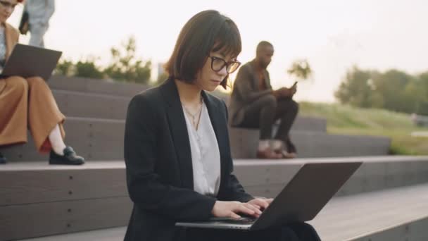 Jovem Empresária Asiática Formalwear Óculos Sentados Assentos Escalonados Parque Digitando — Vídeo de Stock