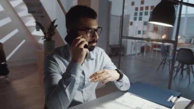 Ofiste geç saatlere kadar çalışırken masasında oturan ve cep telefonuyla konuşan Ortadoğulu sakallı iş adamının 360 derecelik izleme görüntüsü.