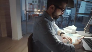 Orta Doğulu genç mimarın kalem kullanıp kare çizerken ofis masasındaki kağıt üzerine 360 derecelik izleme görüntüsü.