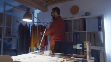 Moda stüdyosunda bayan meslektaşımla çalışırken Orta Doğulu erkek tasarımcının cep telefonuyla konuştuğu 360 derecelik bir izleme görüntüsü.