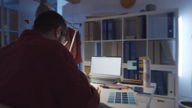 Orta Doğulu yakışıklı bir erkek tasarımcının masa başında resim çizerken ve geç saatlere kadar karanlık stüdyoda çalışırken bayan meslektaşlarıyla konuşurken 360 derecelik bir izleme görüntüsü.