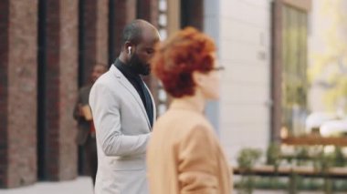 Resmi takım elbiseli ve kablosuz kulaklıklı Afro-Amerikan işadamı. Şehir caddesinde durmuş kahve içip akıllı telefon kullanıyor.