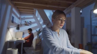 360 derecelik güzel bayan tasarımcının kablosuz kulaklık takıp gece moda stüdyosunda çalışırken akıllı telefondan müzik dinlerken görüntüsü.